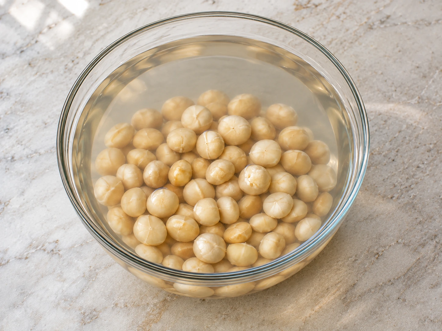 Four cups raw macadamias fully submerged beneath at least two inches of warm salted water