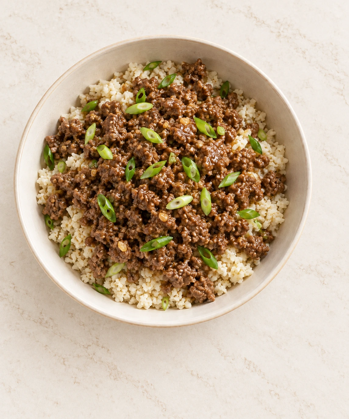 Near-overhead Full GAPS Asian beef bowl with cauliflower rice and green onion tops