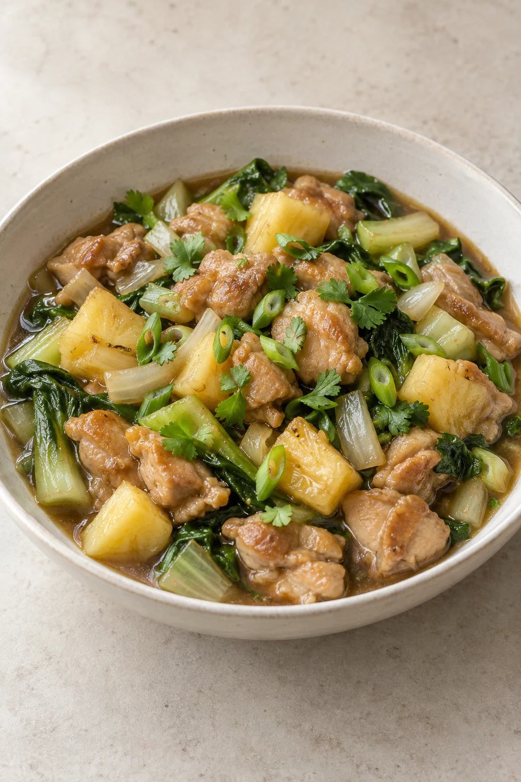 Pineapple date sweet and sour chicken with bok choy in a cream serving bowl