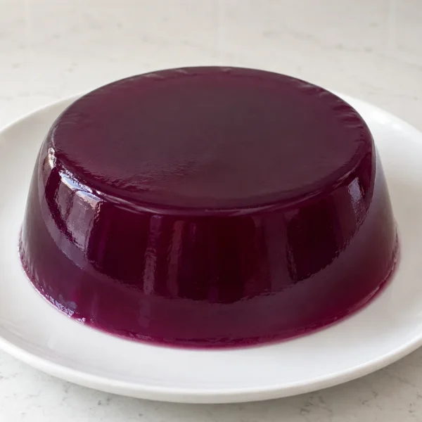 Whole deep-purple Concord grape gelatin on a white ceramic plate