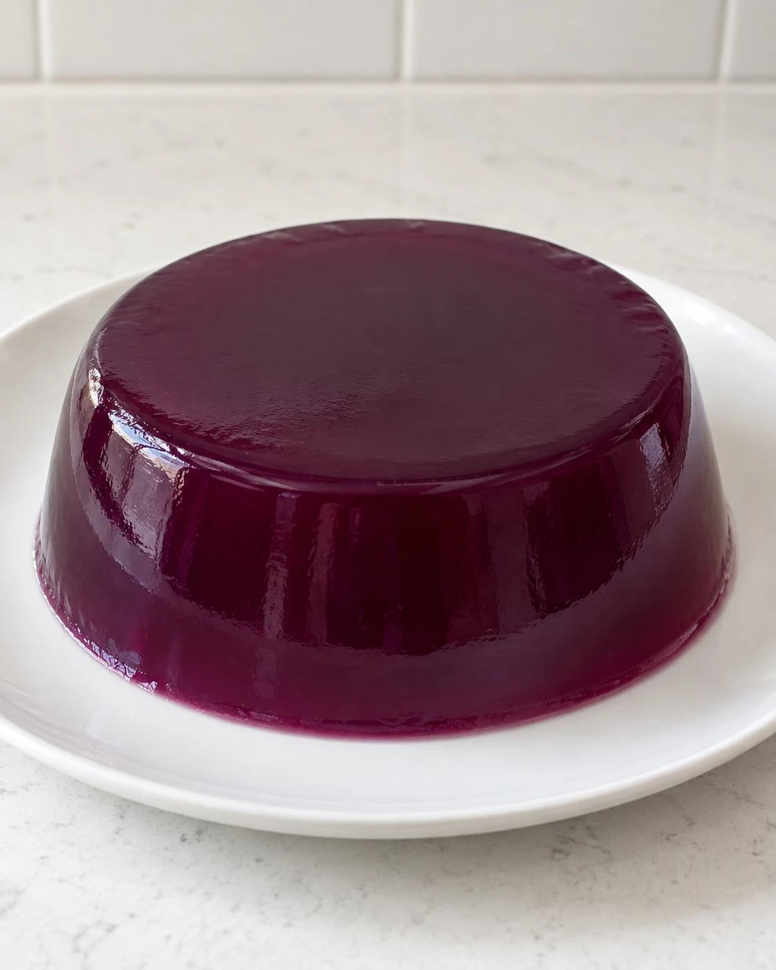 Whole deep-purple Concord grape gelatin on a white ceramic plate