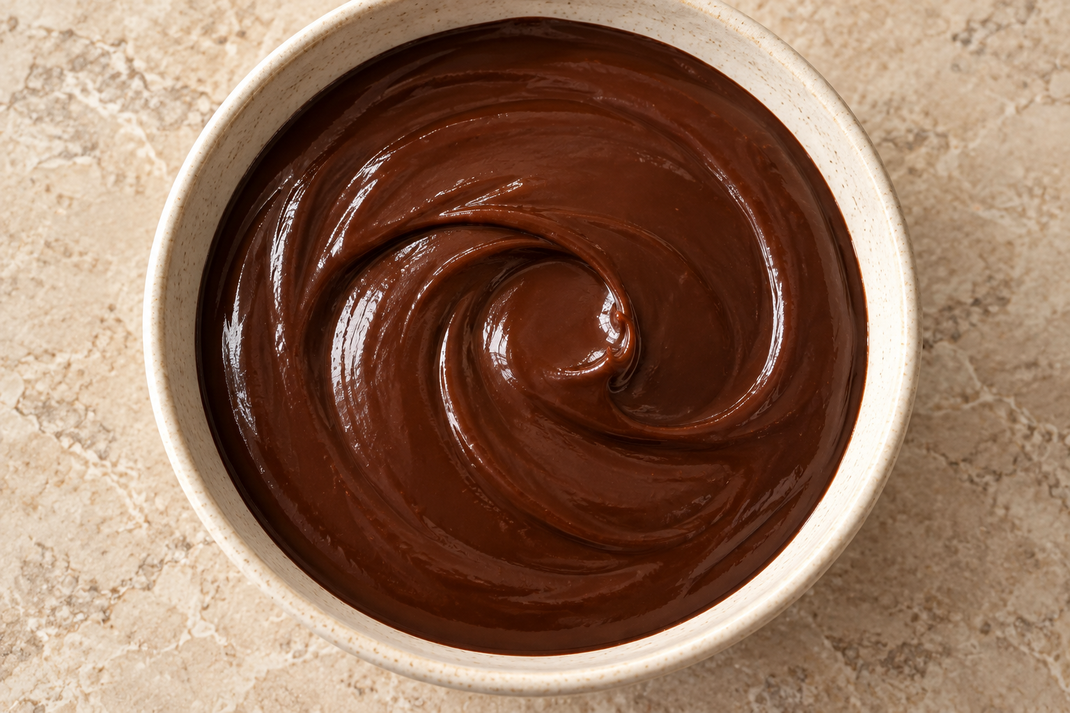 Overhead coconut-milk cocoa ganache holding a curved glossy ribbon trail