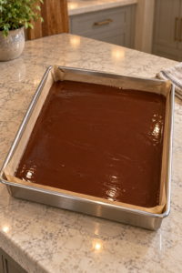 Smooth honey-sweetened cocoa-butter chocolate mixture resting in a parchment-lined stainless pan